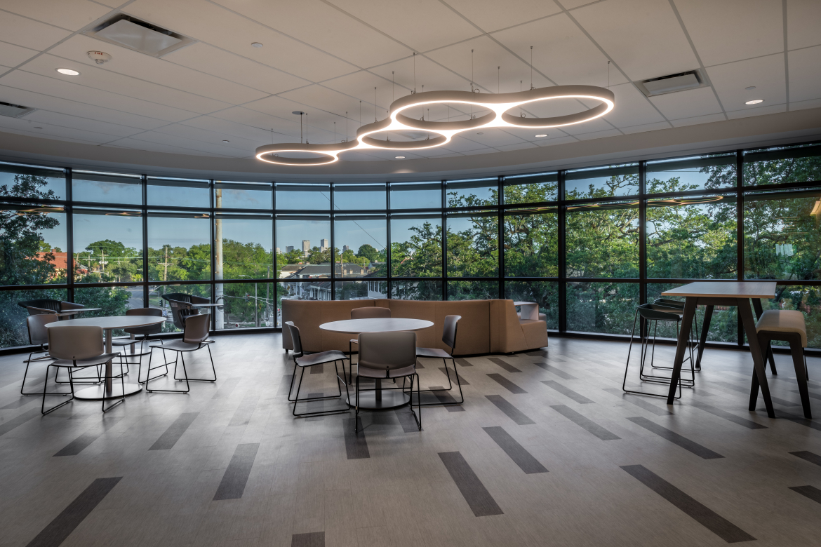 Lounge area with floor to ceiling windows overlooking tree canopy.